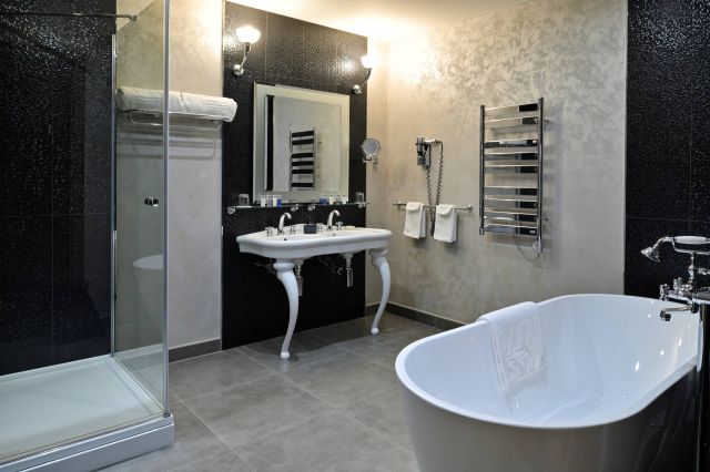 Modernes Badezimmer mit Badewanne, Dusche, elegantem Waschbecken und stilvoller Dekoration in neutralen Tönen.