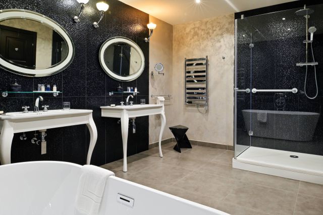 Salle de bain moderne avec doubles vasques, douche élégante, baignoire indépendante, miroirs raffinés et décoration stylée.