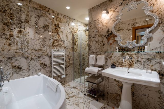 Une salle de bains luxueuse avec des murs en marbre, une baignoire autoportante, des équipements modernes et une décoration élégante.