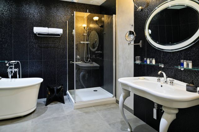 Salle de bain moderne avec baignoire autoportante, douche en verre, lavabo élégant et touches noires stylées.