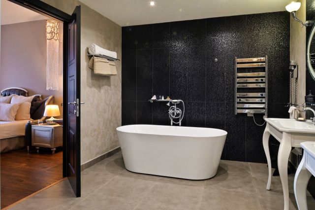 Modern bathroom featuring a freestanding tub, sleek fixtures, and stylish decor, adjacent to a cosy bedroom.