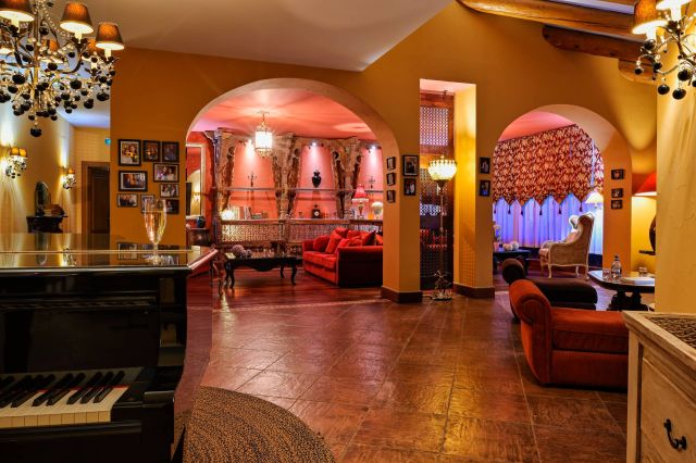 Elegant interior with arched openings, cozy seating, and warm lighting, showcasing a rich colour palette and decor.