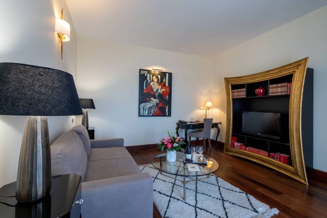 Ein stilvolles Wohnzimmer mit einem grauen Sofa, eleganter Dekoration, einem runden Couchtisch und modernen Regalen.