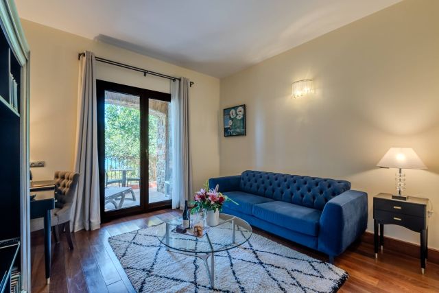 Un salon confortable avec un canapé bleu, une table basse en verre et un balcon offrant des vues panoramiques. La lumière naturelle entre magnifiquement.