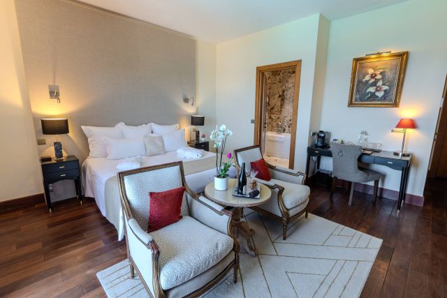 Une chambre d'hôtel élégante avec un grand lit, un coin salon, des œuvres d'art et des équipements modernes. Design chaleureux et accueillant.