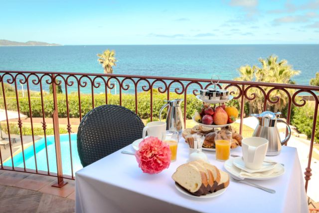 Ein wunderschönes Frühstücksbuffet mit Gebäck und Obst, mit Blick auf einen ruhigen Ozean von einem Balkon.