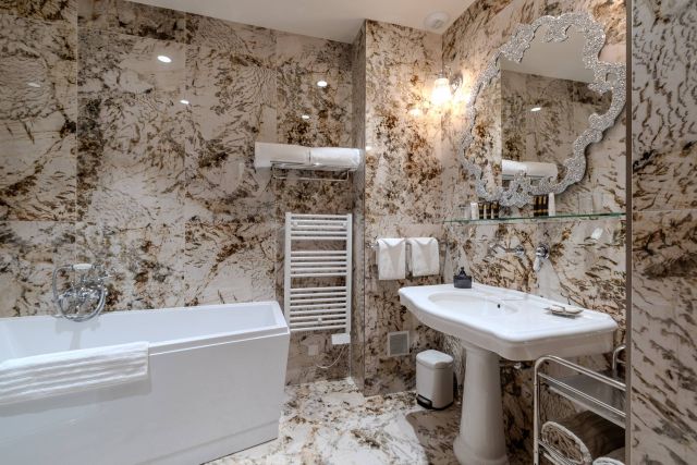 Salle de bain luxueuse avec un design en marbre, des équipements modernes, une baignoire blanche et des accents de miroir élégants.