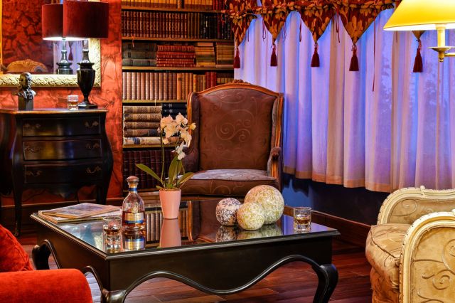 Une chambre cosy avec des meubles vintage, une bibliothèque, une décoration élégante et une table basse design avec des boissons.