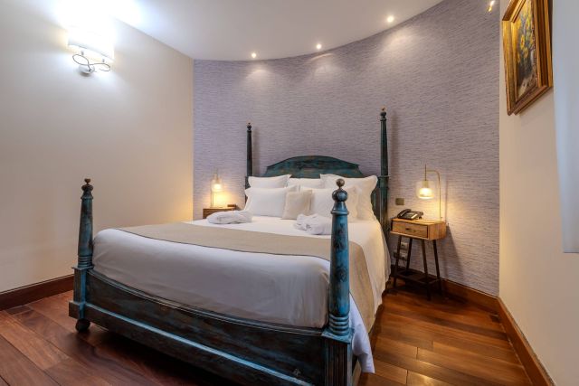 A cosy bedroom featuring a rustic bed, warm lighting, and elegant decor, creating a serene atmosphere.