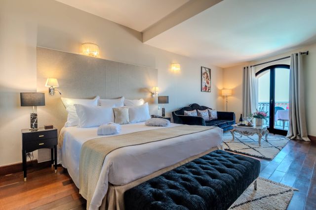 Elegant bedroom featuring a plush bed, cozy seating, and a balcony, decorated with soft lighting and stylish furnishings.